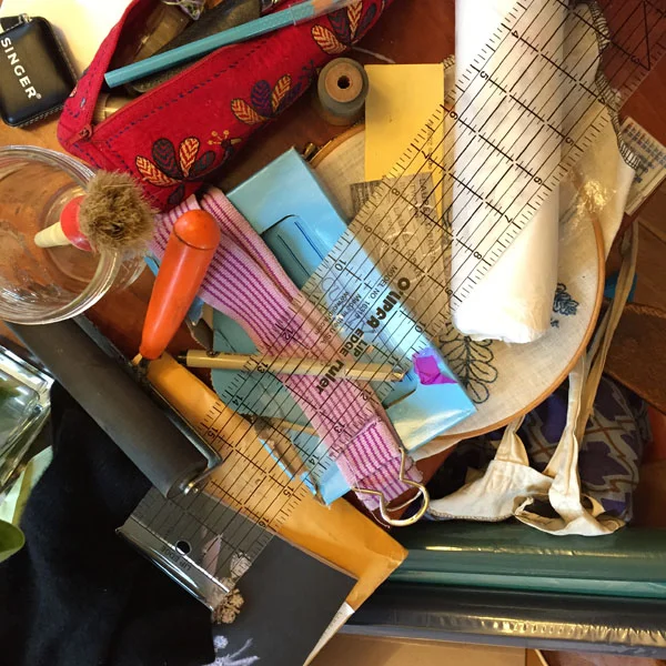 The current scene at my end of the dining room table. Up there: knitting, sewing, bookbinding, sewing machine repair, and a broken belt belonging to a kid.&nbsp;