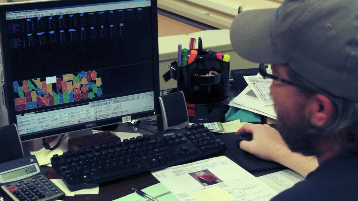  A worker then takes each individual uniform piece and - using a computer - tightly arranges them on the cloth they will be cut from. The computer then sends cutting directions to the cutter. Because each uniform is unique in design and size, there a