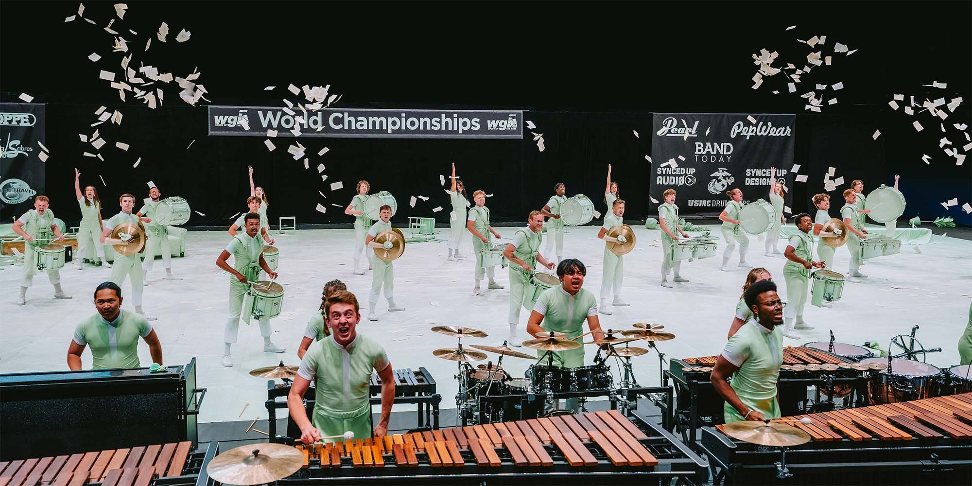 Rhythm X performers in the final set of their 2026 production, screaming after having played their last note. Book pages are flying in the air.