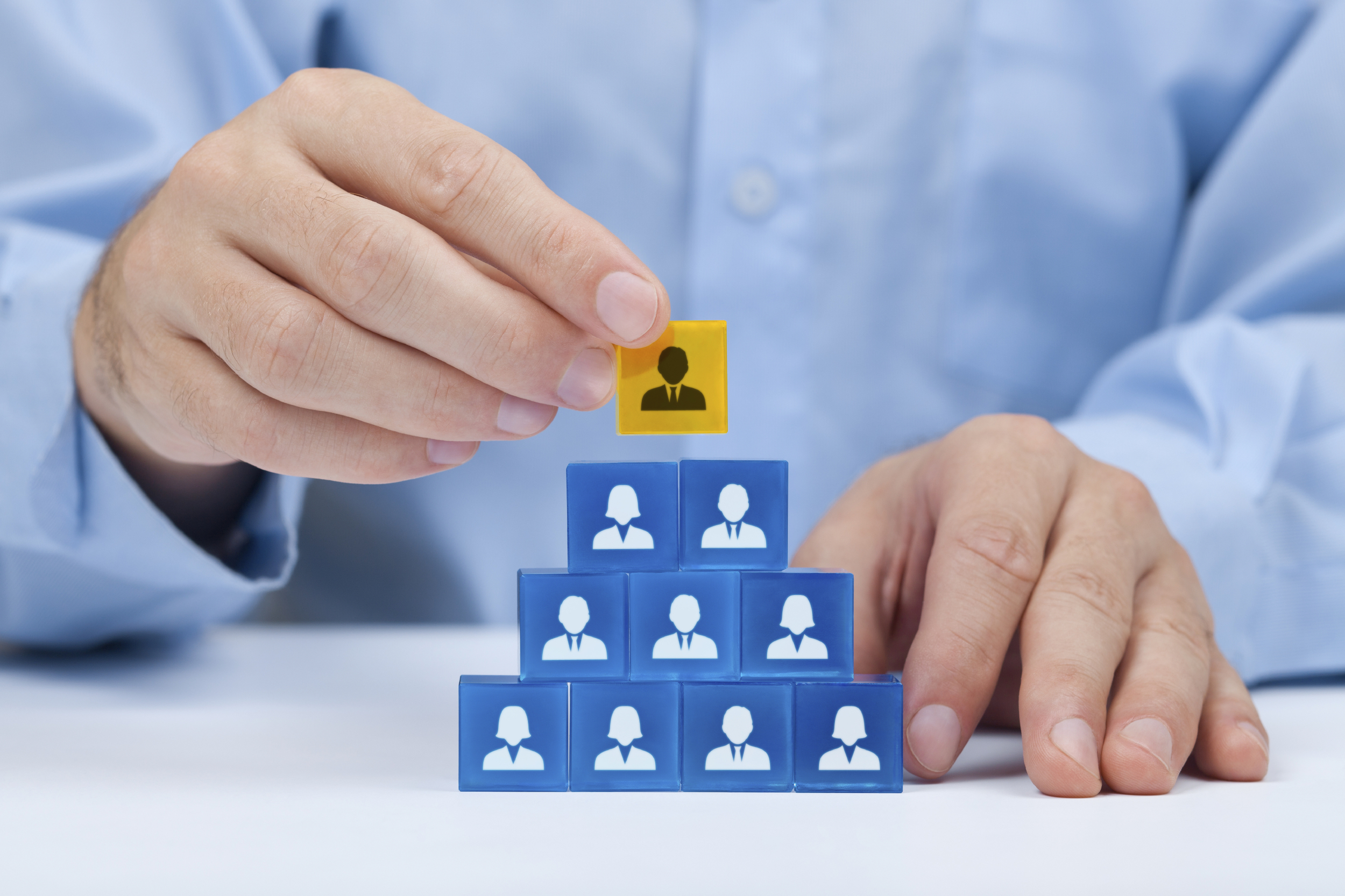 A stack of blocks representing managers in a business with a yellow block on top representing the CEO, Managing Director or Corporate Board