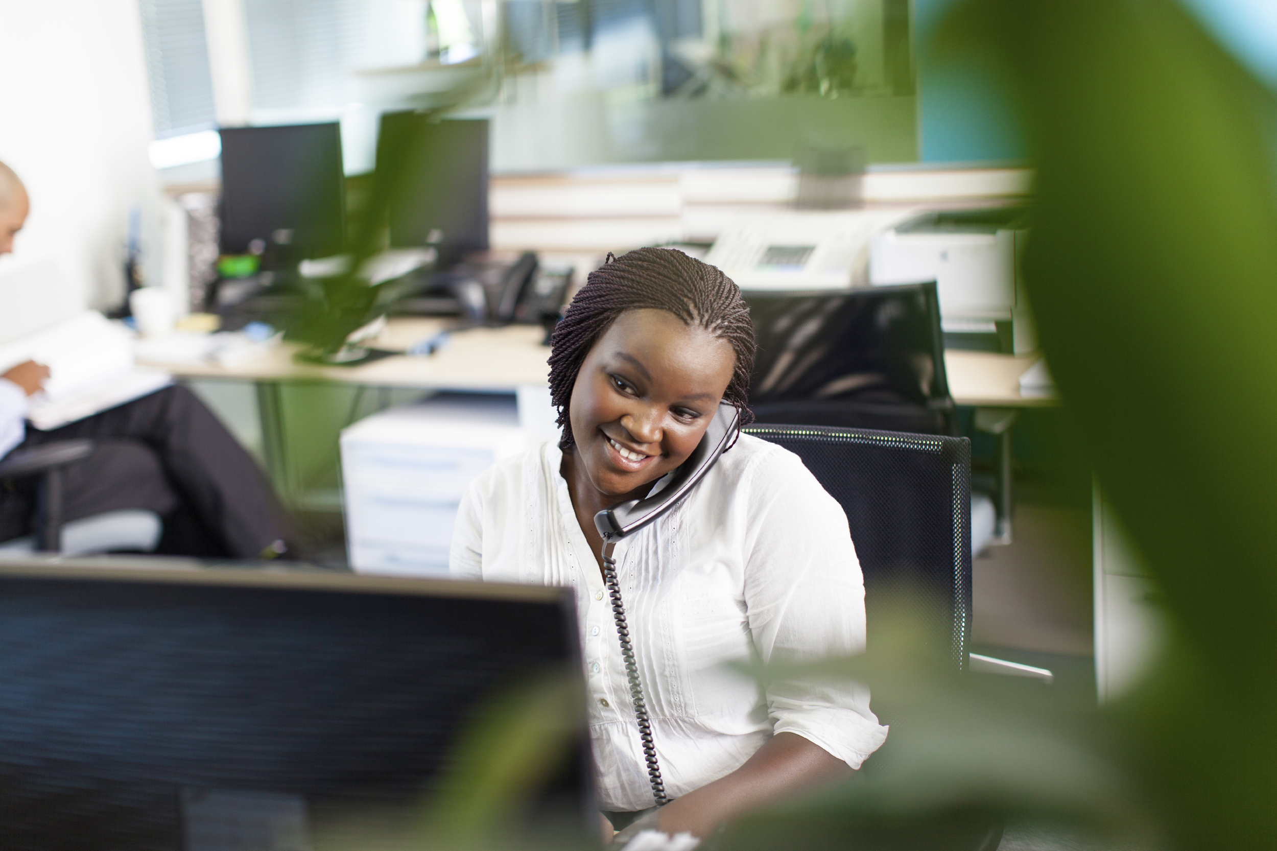 Woman on phone in front of a computer sorting out IT problems