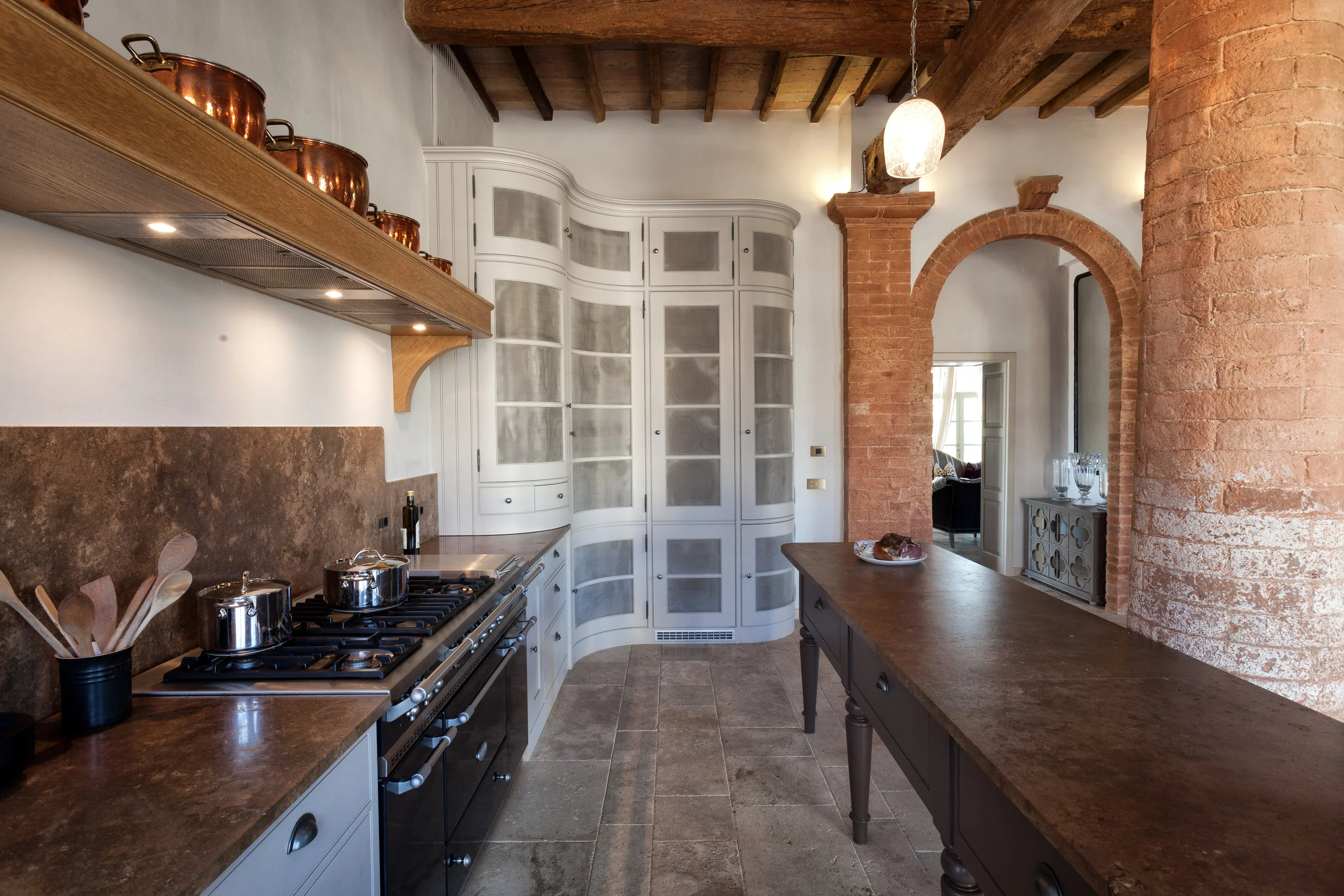 The elegant curved tall cupboards sit perfectly with the huge stone pillars in the kitchen