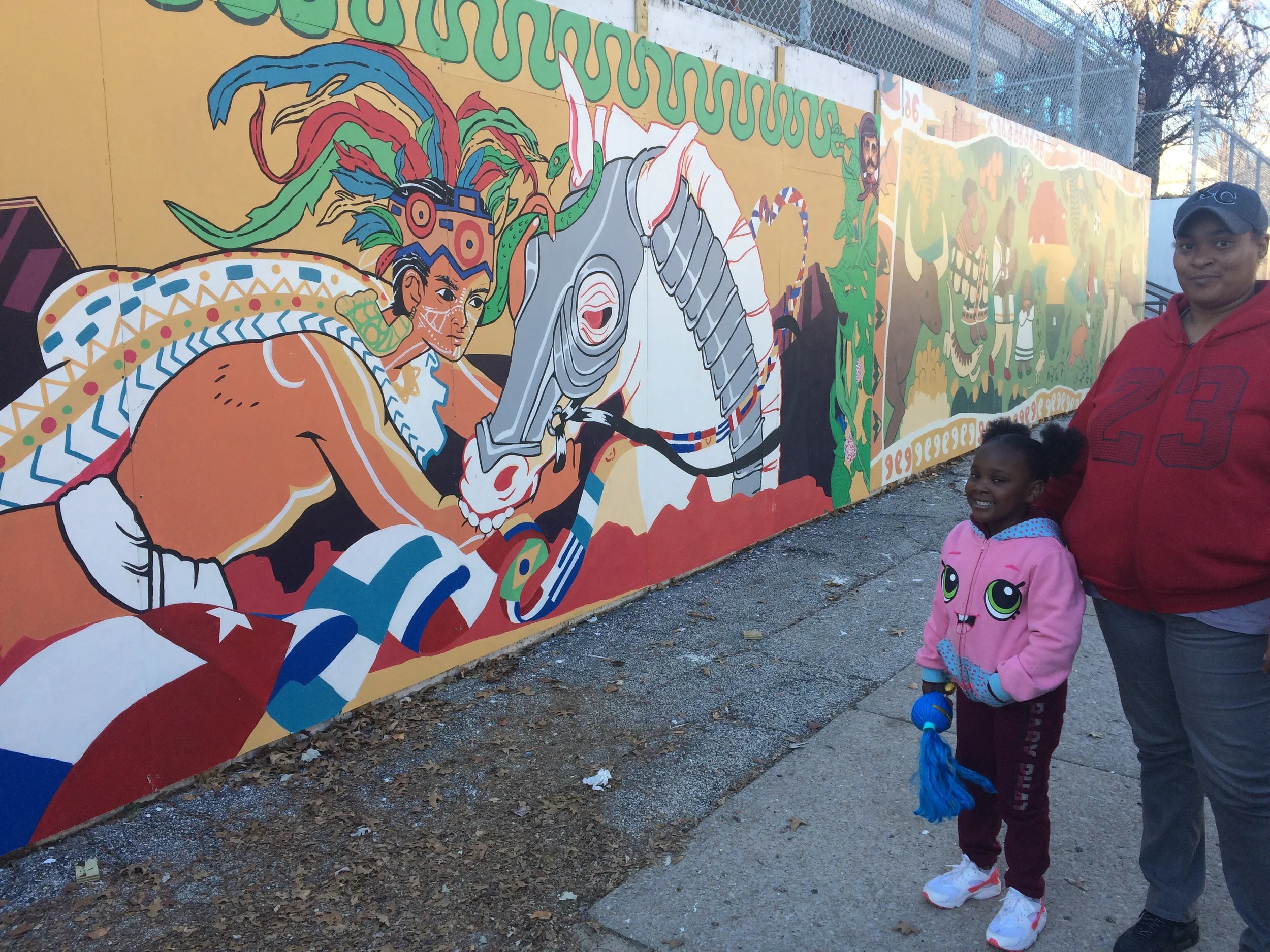 A mother and daughter out for a walk in their neighborhood stop by the mural