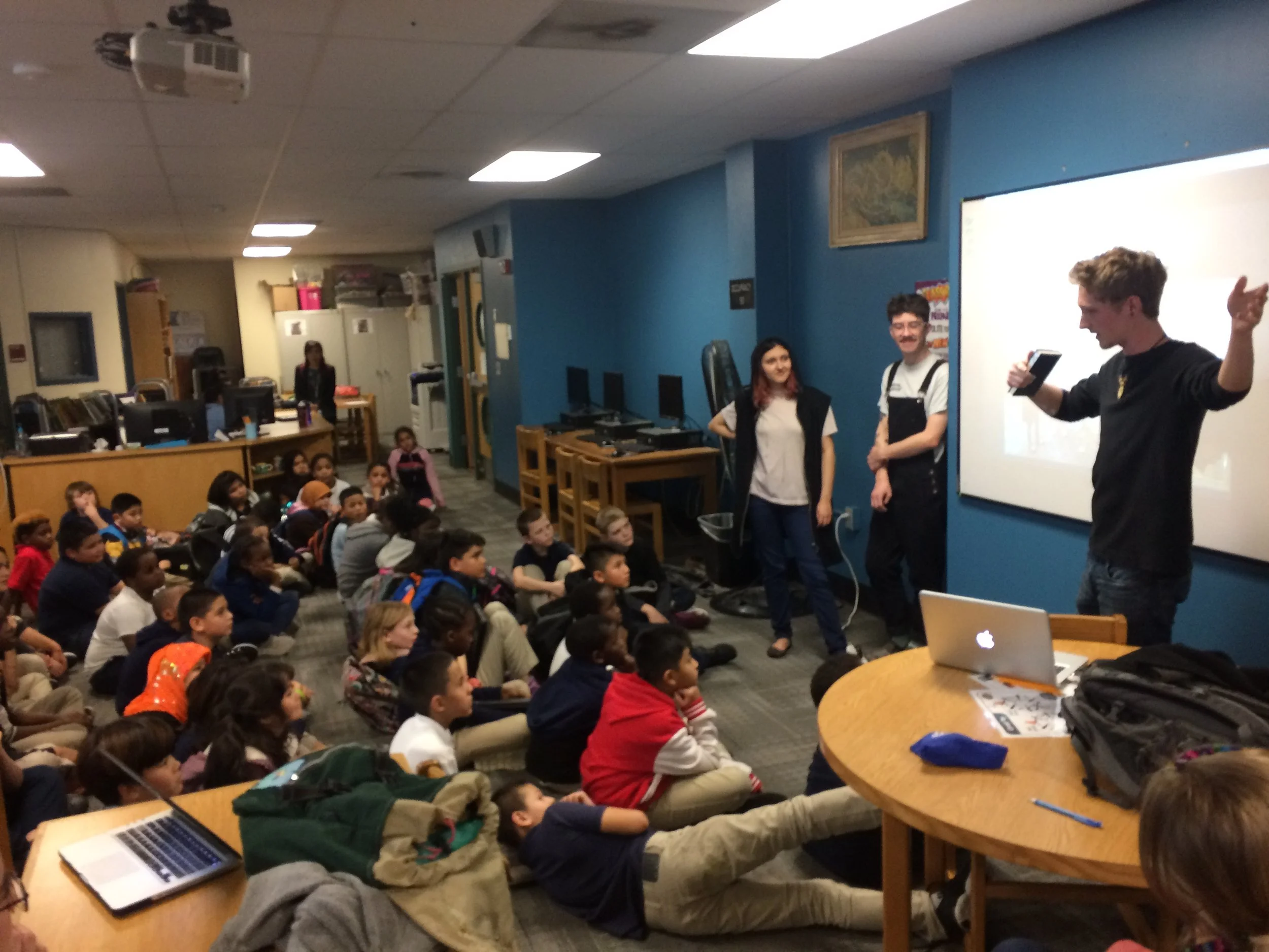 KCAI Illustration junior Eli Harris talking to the kids at Whittier about his teams' mural