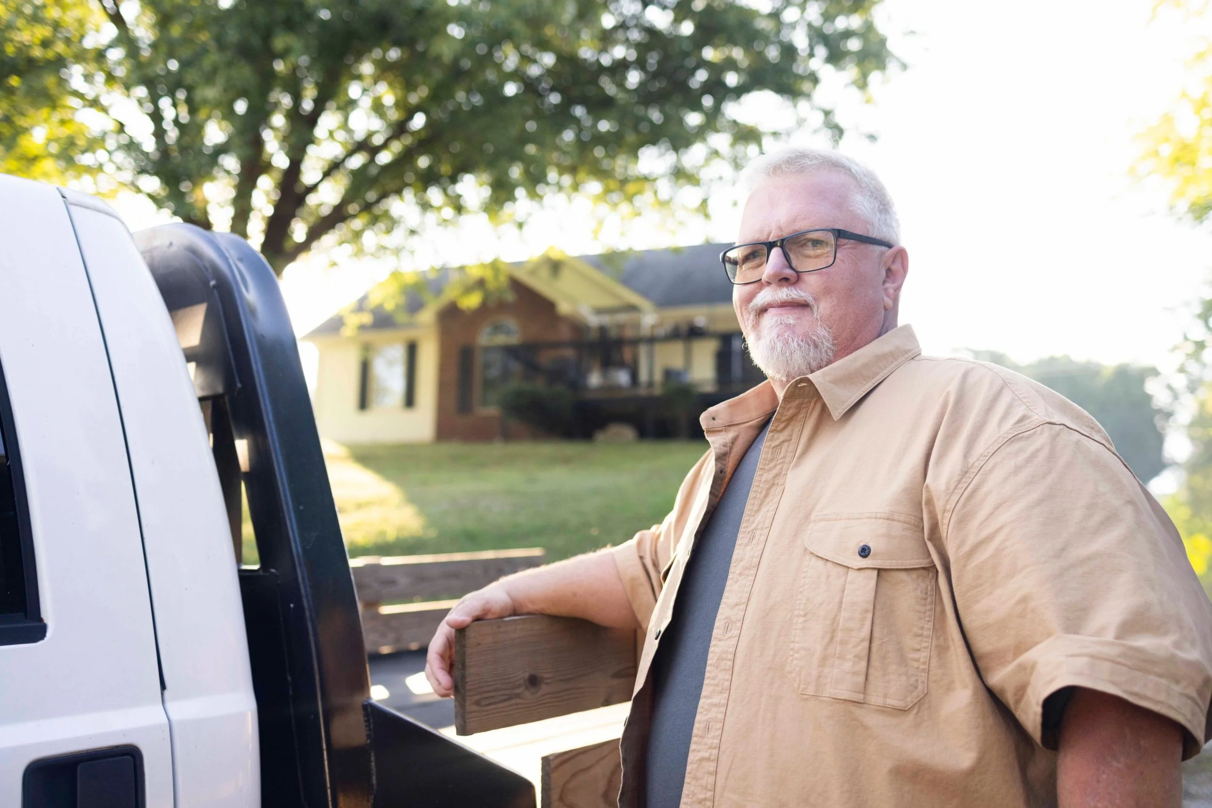 Lifestyle portrait for a Dupixent patient story: man leaning on a flatbed truck in front of his home