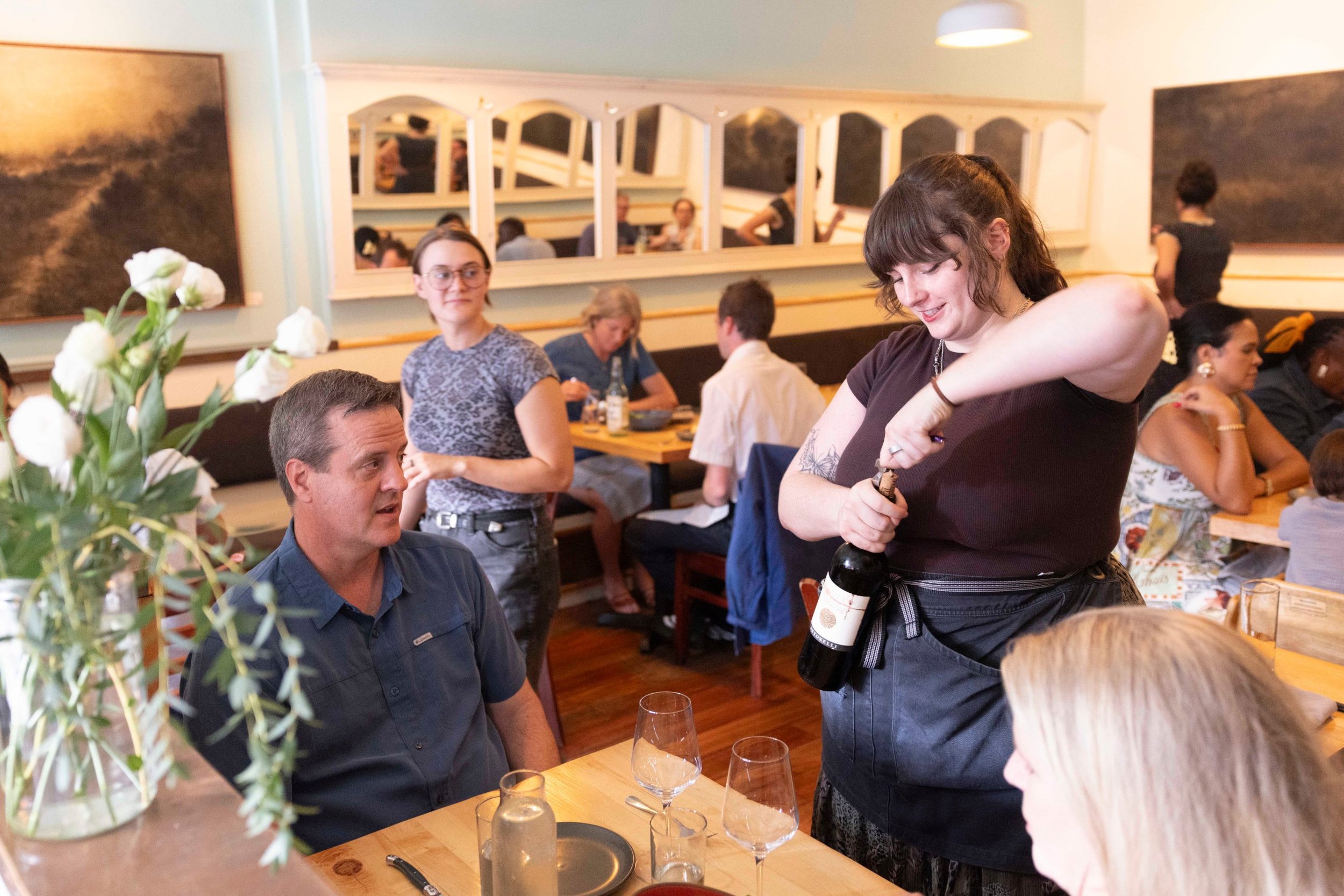 Asheville restaurant photography: server opening a bottle of wine at a dining room table