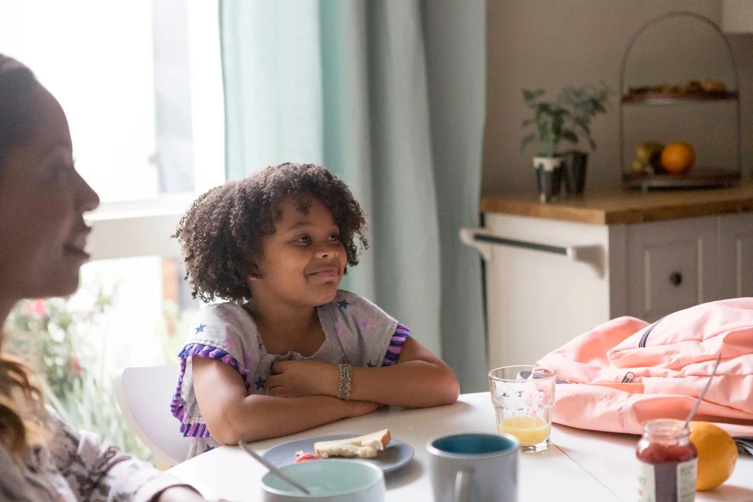 Healthcare lifestyle photography: smiling girl at a kitchen breakfast table with her family