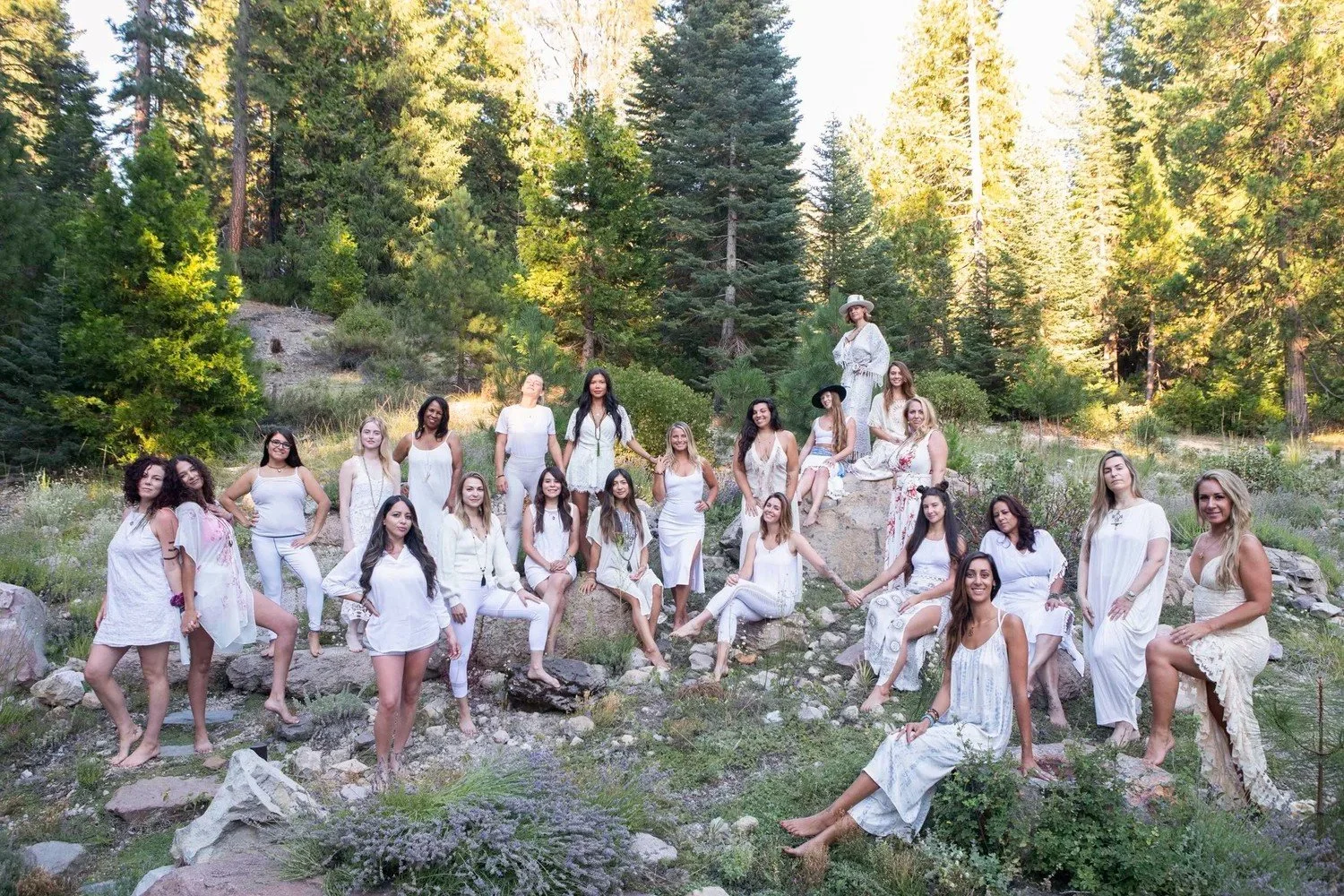 Large group of women dressed in white posing among pine trees and rocks, Mount Shasta women's retreat group photography