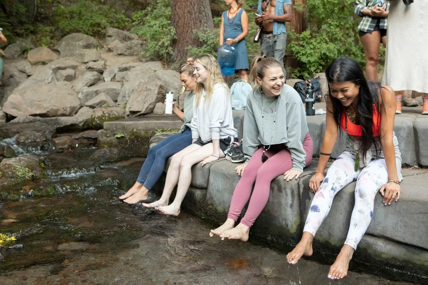 Women sitting on a stone ledge dipping their feet in a creek, Mount Shasta women's retreat photography