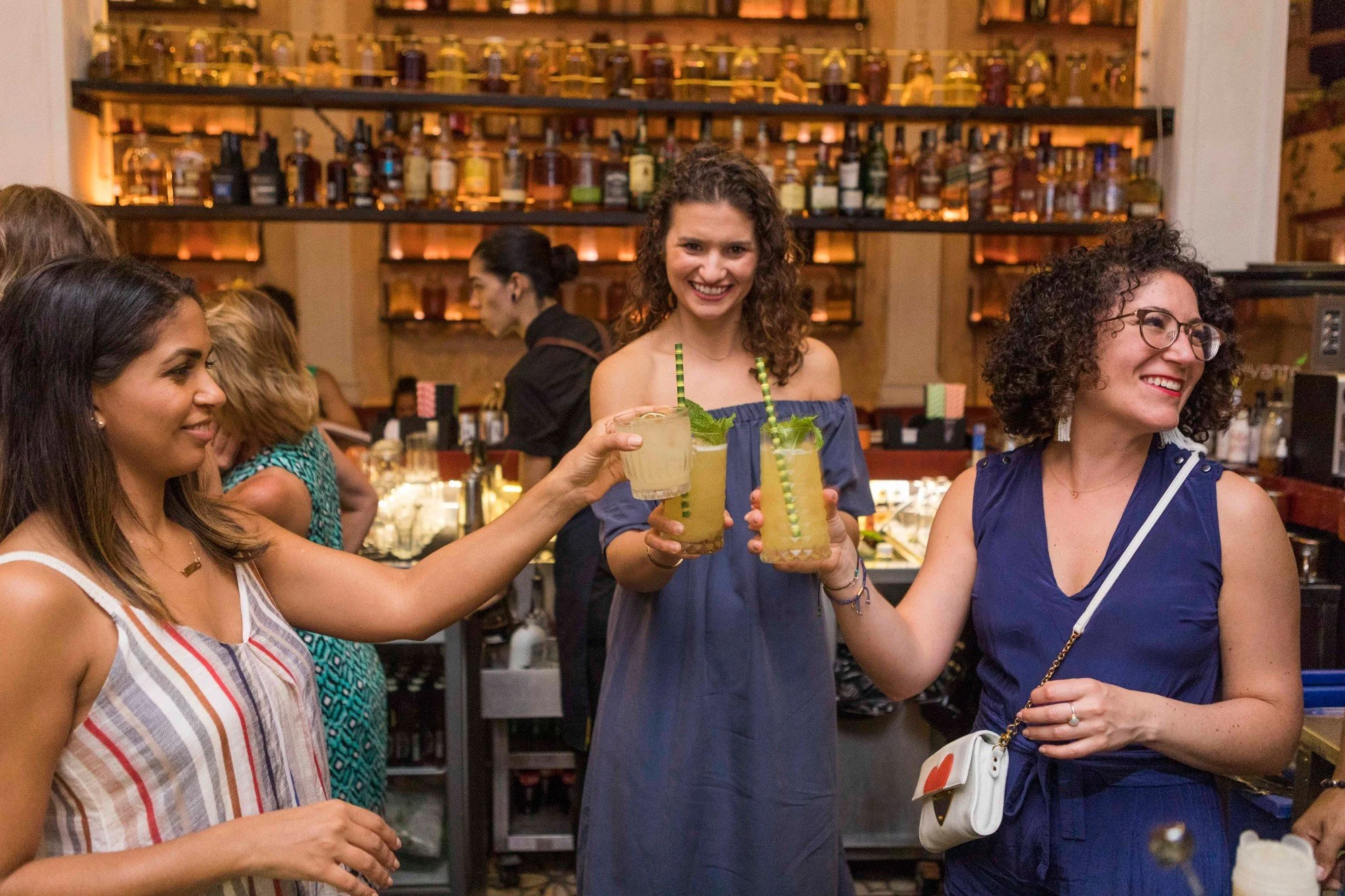 Women toasting with cocktails at a bar, group travel photography in Colombia