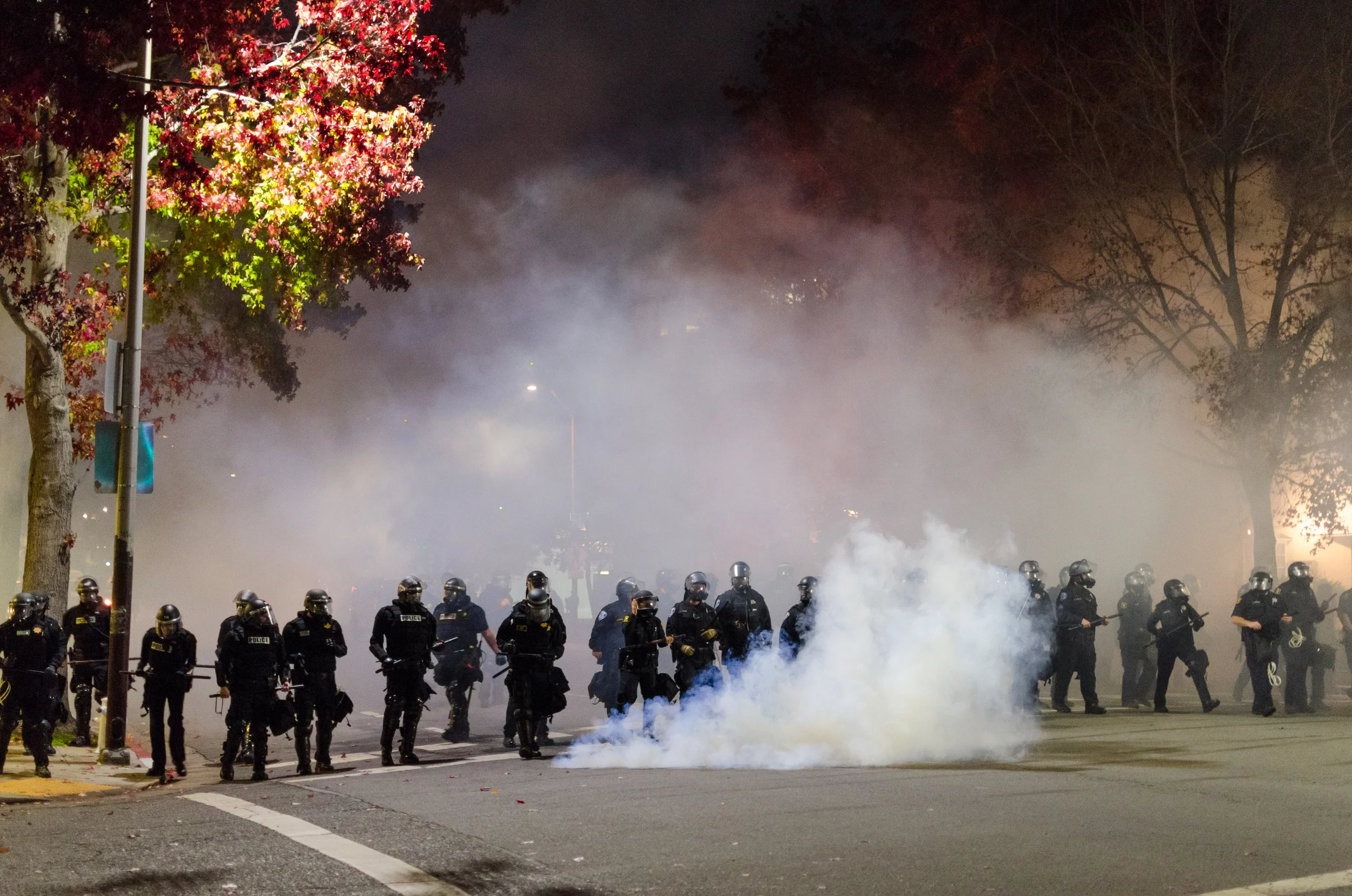 Line of gas masked police marching through tear gas towards a crowd of fleeing protesters on December 6th, 2014 in Berkeley, CA - photo by Kyle Cameron