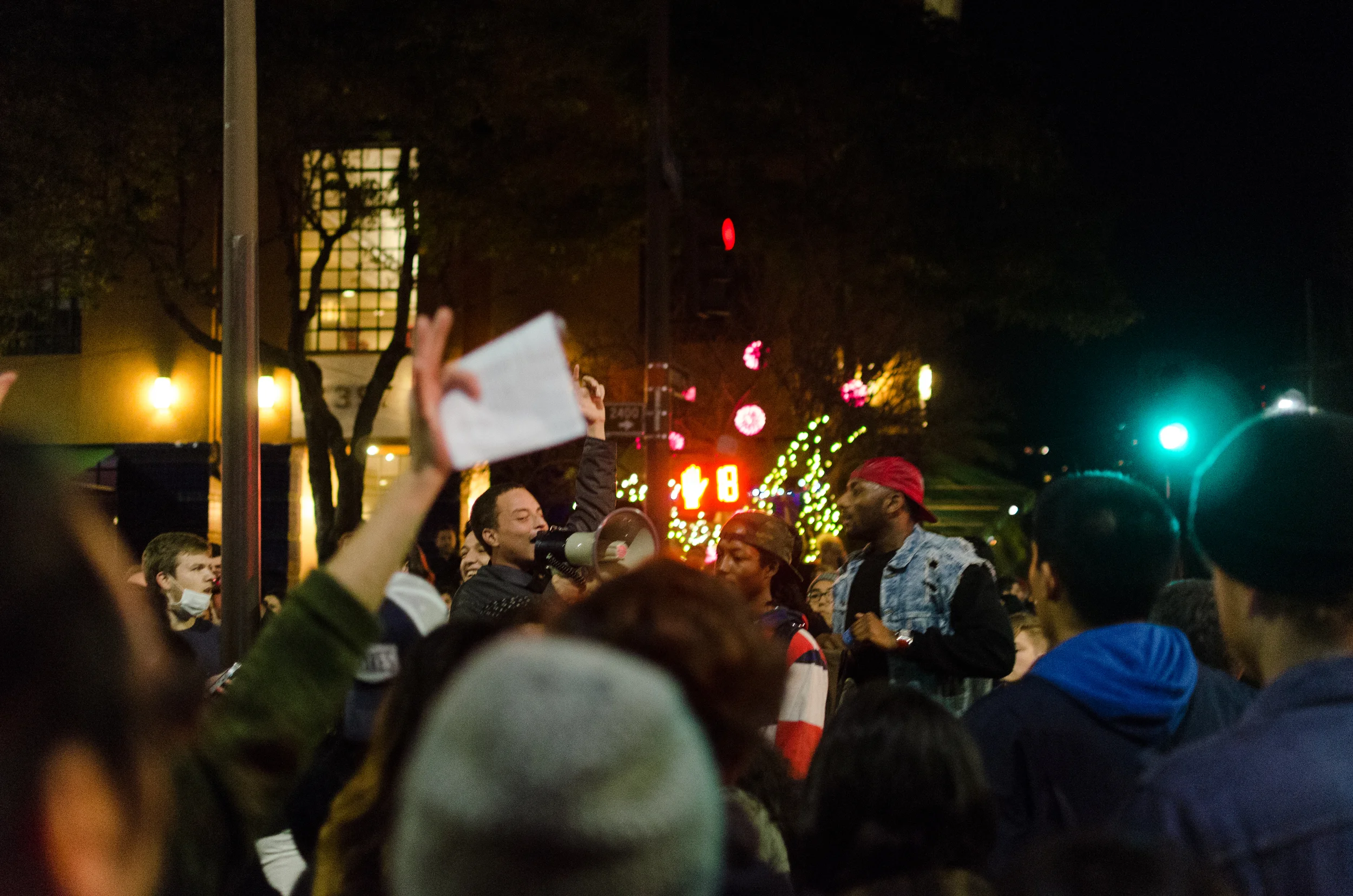 One of the men with a megaphone trying to speak to the crowd in front of the Berkeley Police Station on the night of December 8th, in Berkeley, CA - photo by Kyle Cameron