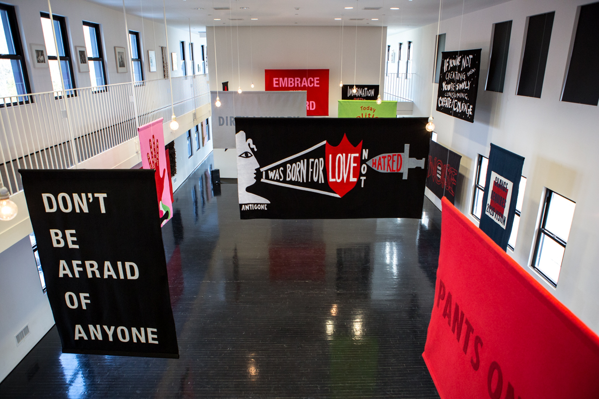 Word on the Street at The Watermill Center , 2017, felt political banner exhibition, House of Trees art collective (Amy + Jennifer Khoshbin). Banners on view in this image: Don’t Be Afraid of Anyone : Laurie Anderson + A.M. Homes, I was born for love not hatred : Amy Khoshbin + Anne Carson, If you’re not creating, you’re simply consuming, create with courage : Wangechi Mutu, Change Requires 2020 Vision : Carrie Mae Weems, Pants on Fire : Jenny Holzer, Open Palms Hold More : Naomi Shihab Nye + House of Trees, Quiet Lives Inside Noise : Naomi Shihab Nye + HOT