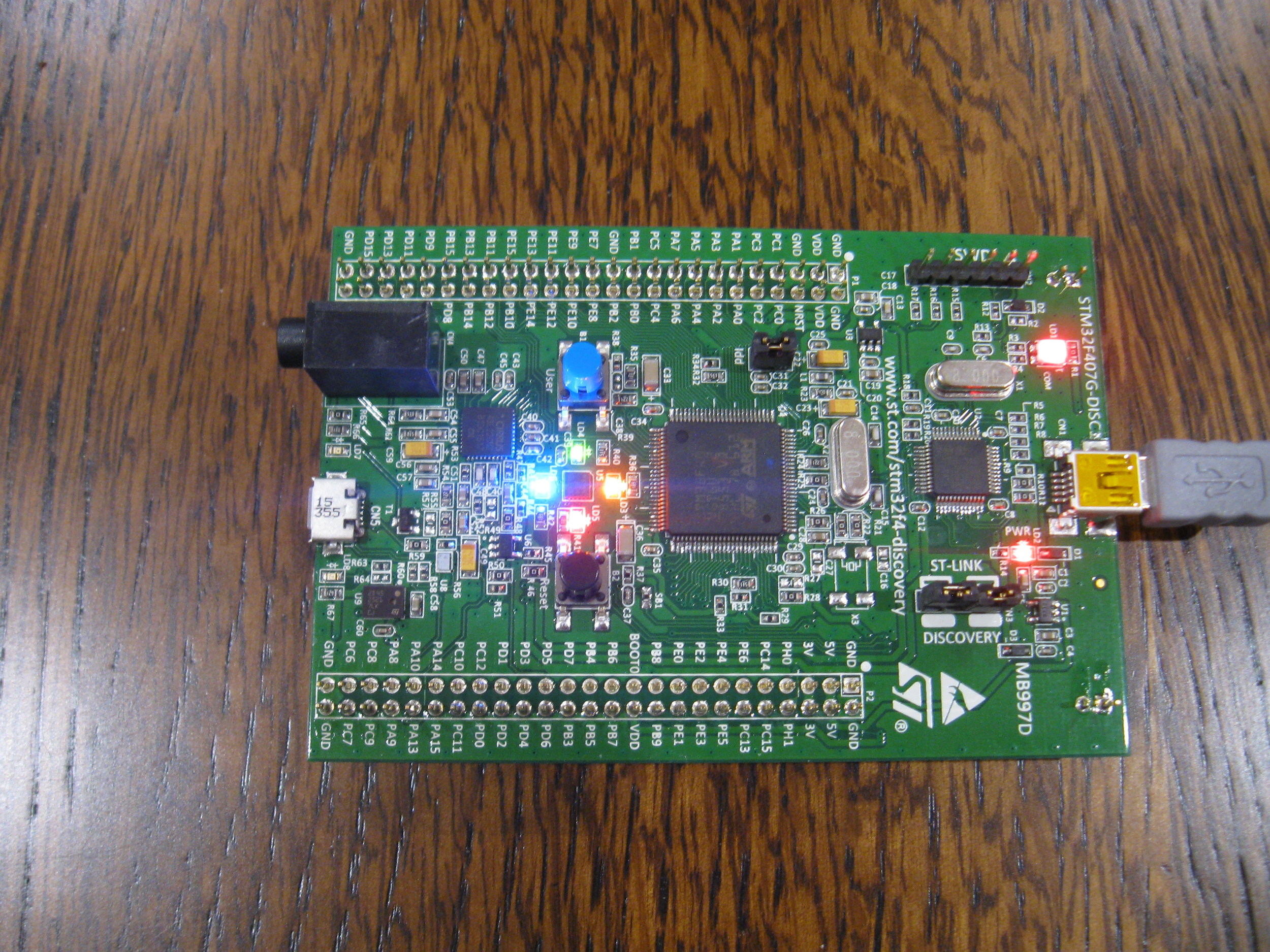 The DISC1 board running canned sample code, lighting the 4 LEDs that surround the accelerometer.