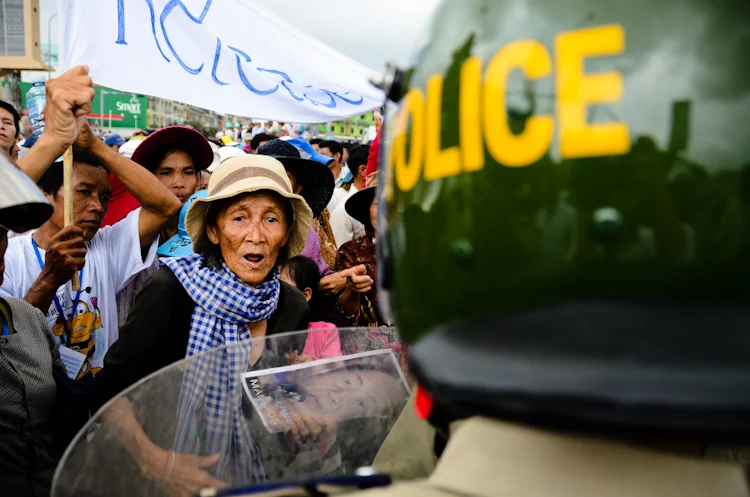 A woman faces police outside Phnom Penh Municipal Court House. Supporters of jailed broadcaster Mam Sonando gathered to protest against his detention.