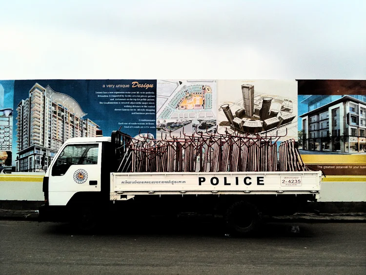 A police vehicle is parked in front of advertisements for a building development near where supporters of broadcaster Mam Sonando were protesting in central Phnom Penh.