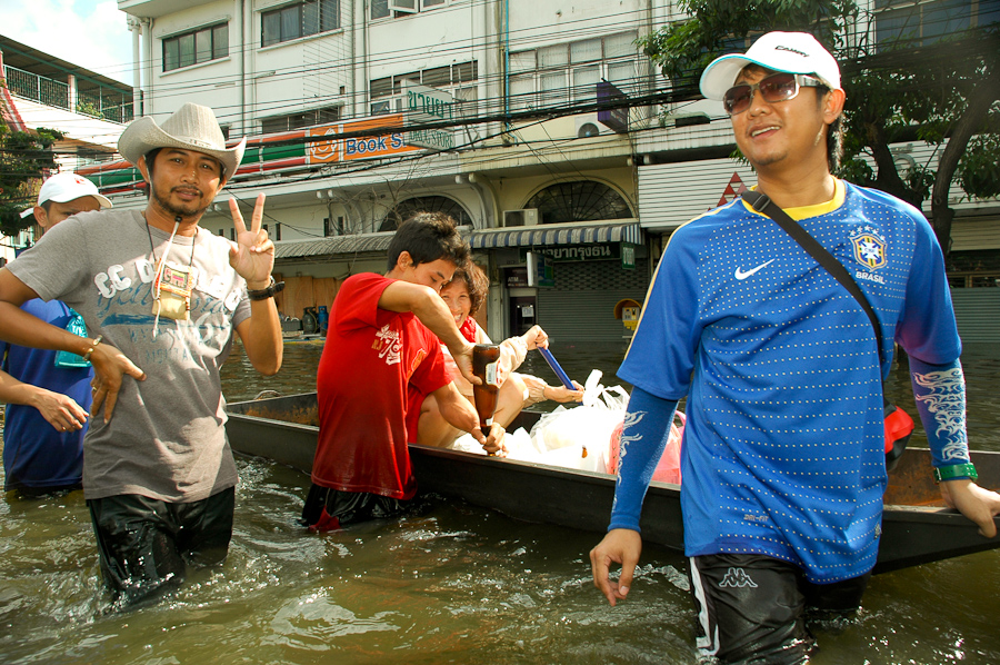  Bangkok residents float supplies in to their homes in a flooded neighborhood, while enjoying a drink. 
