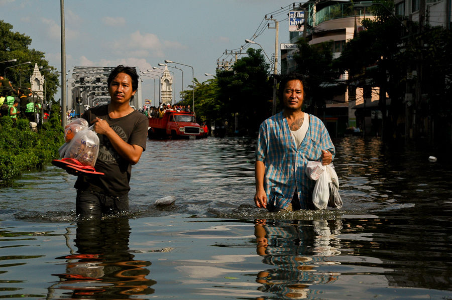  Residents bring supplies into a flooded neighborhood in western Bangkok. 