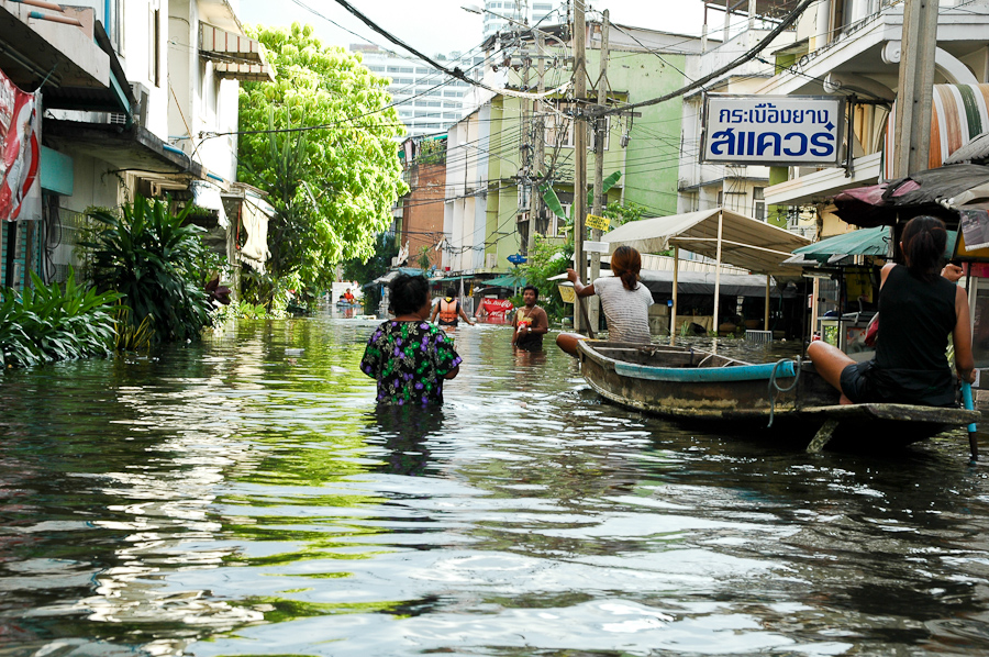  Residents walk and float through a flooded Bangkok neighborhood. 