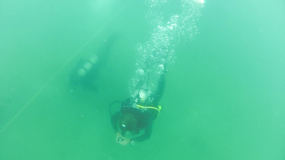  Trainers prepare for a tended dive, a technique for underwater maneuvering in low-visibility conditions. The method involves a tended line manned by a team member on the surface, who can guide divers using line pull signals. 
