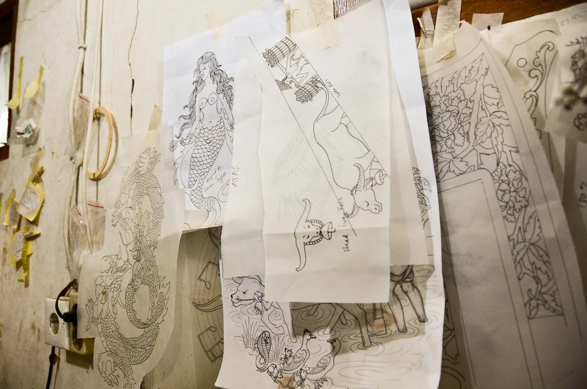 Sketches for designs that will decorate future guitars are taped to the walls of Wayan Tuges's Bali workshop.