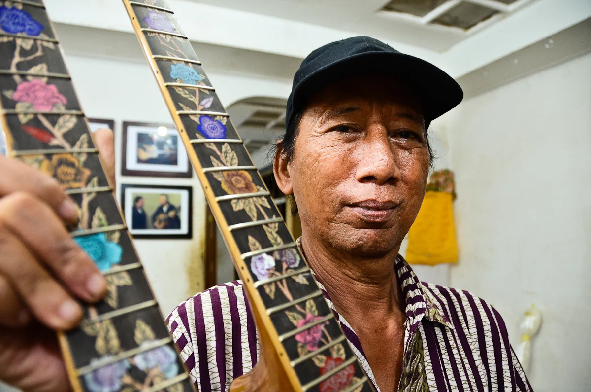Wayan Tuges holds up a prototype for a new guitar: a double-necked acoustic/electric hybrid.