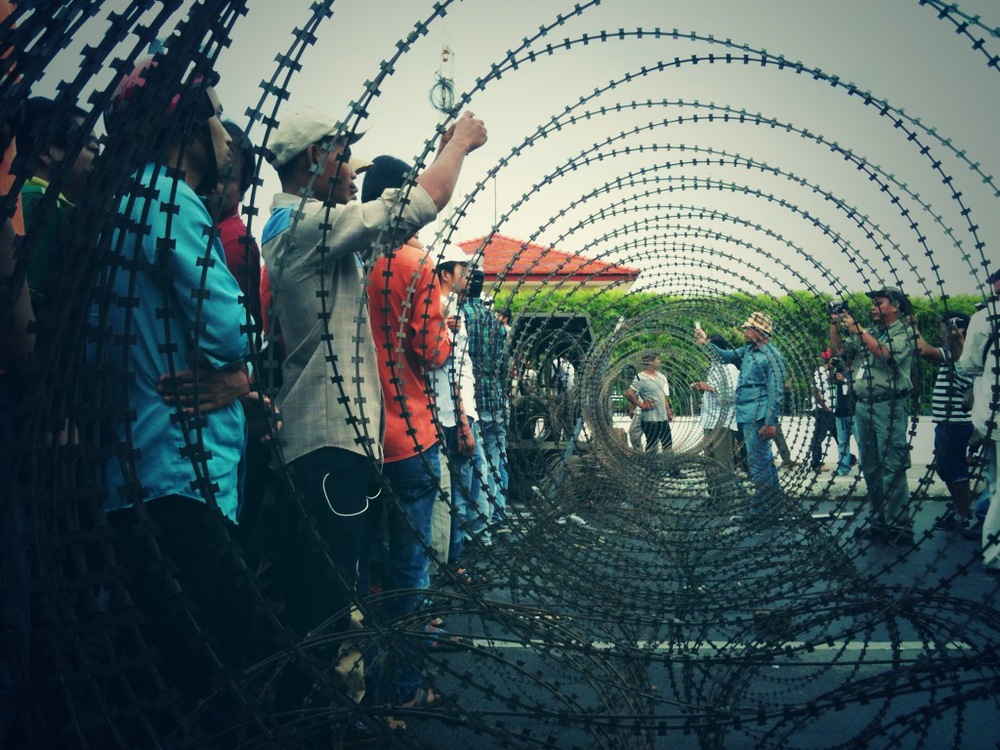  Protesters gather on one side of a barbed wire barricade on Phnom Penh's riverside. 