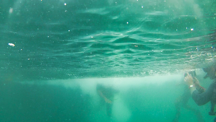 A recruit descends into the water as a dive trainer films his entrance.