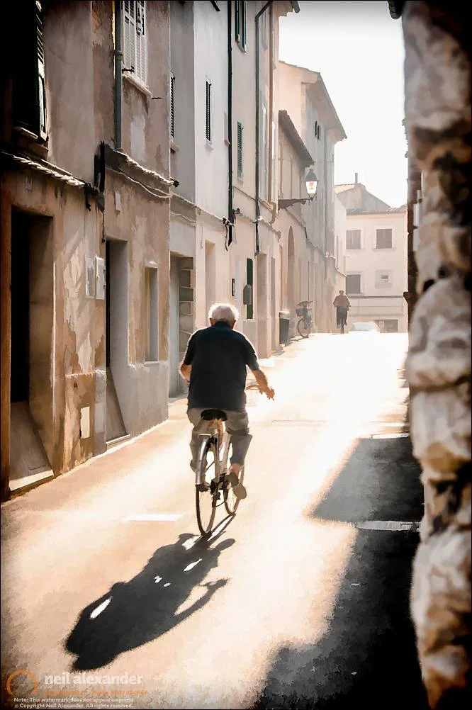 Man riding bicycle in street, Puerto Pollenca, Majorca