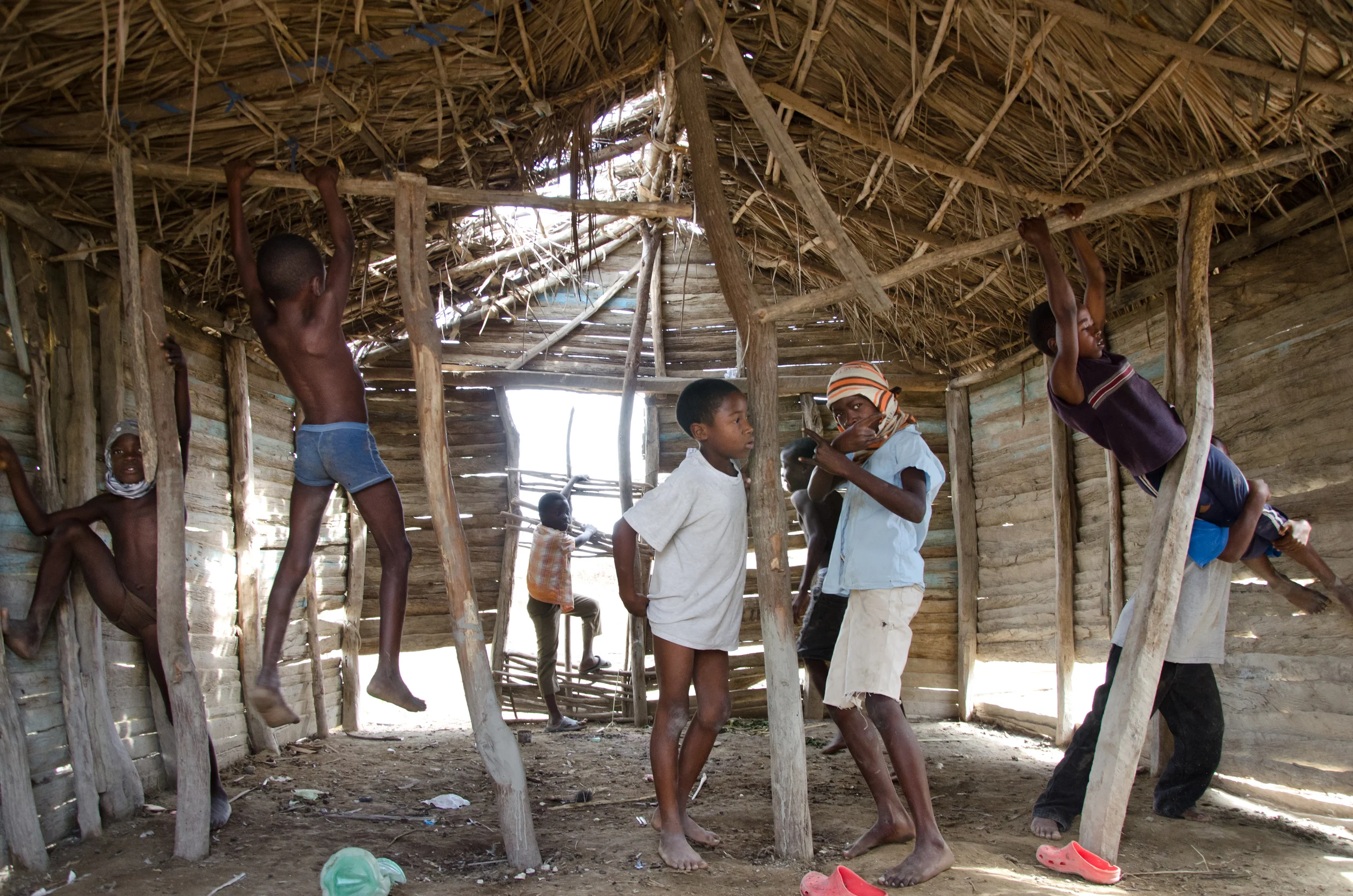  ​Boys from a Haitian sugar cane shanytown play in an abandoned thatch hut near Barahona, Dominican Republic. 