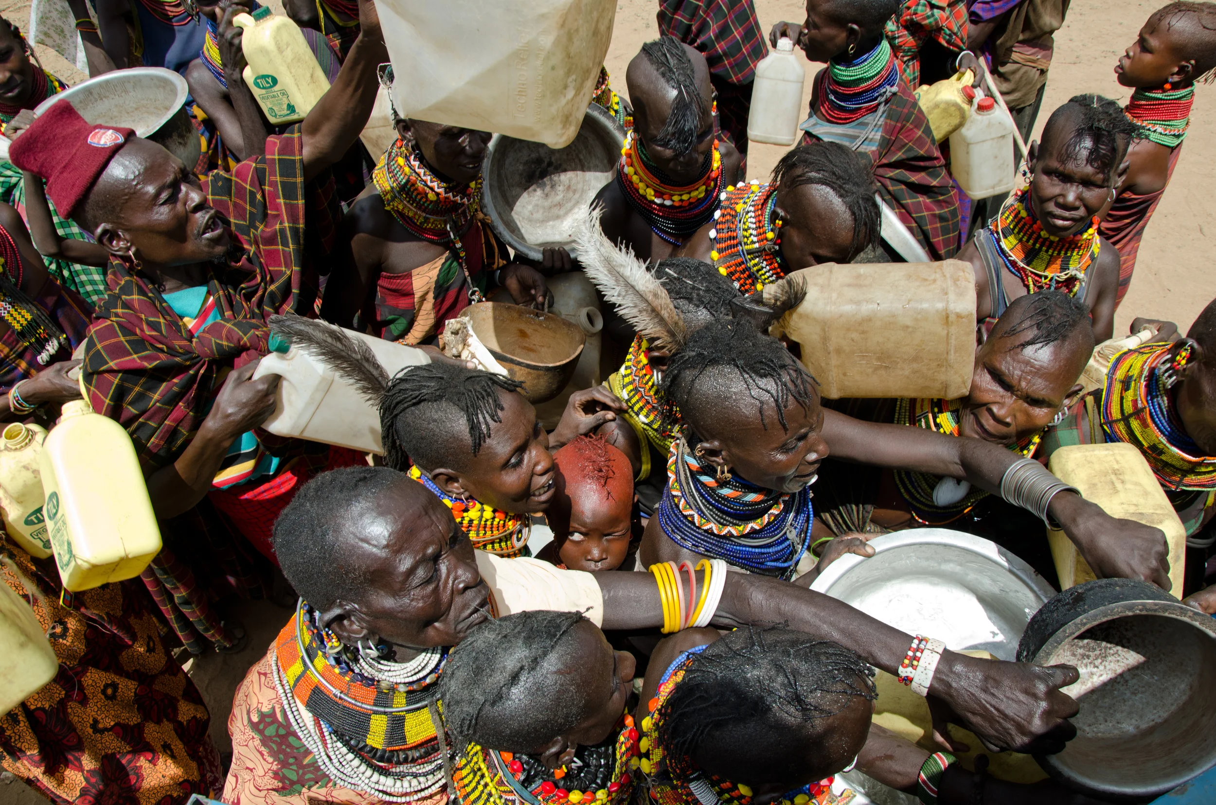  Villagers in Turkana, Kenya scramble to fill jugs of water from a 25,000 liter water truck that comes two times per week. Each family has a ration of 20 liters of water, but ideally they should have 100. The water truck is a temporary intervention w