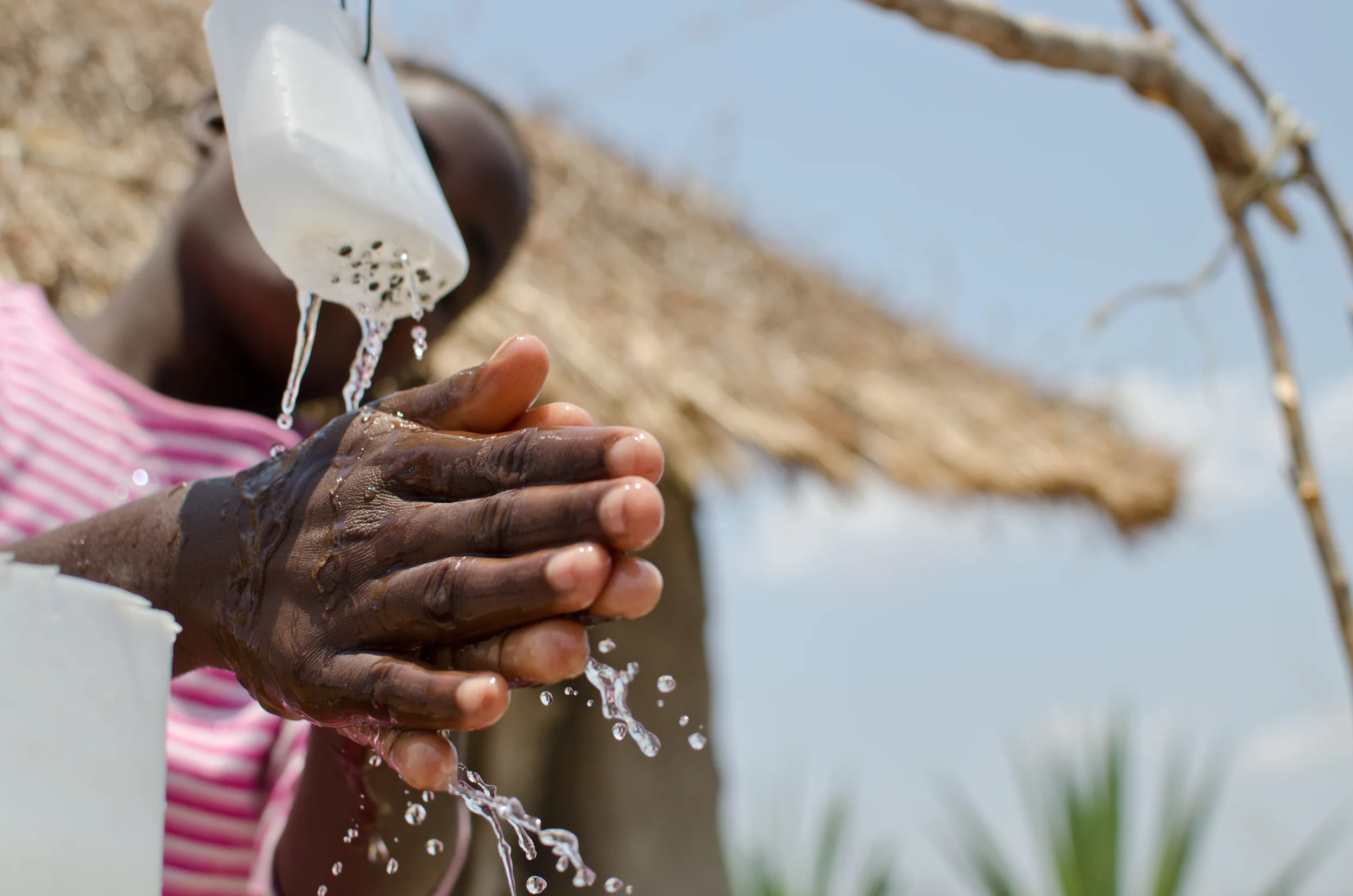  A girl demonstrates the hand washing system her mother devised outside their family's latrine near Lilongwe, Malawi.&nbsp; 