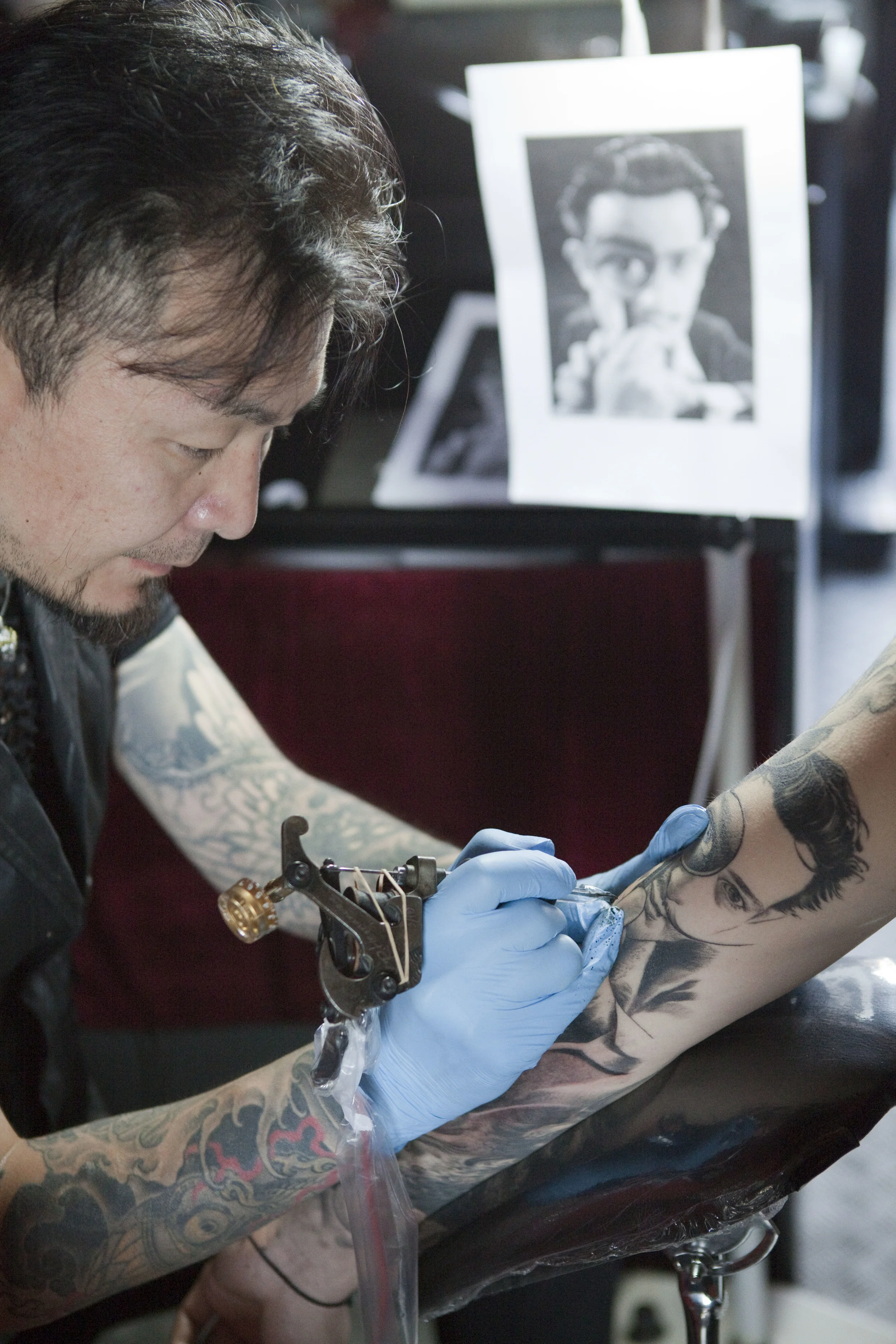  Xiao Long refers to a print-out photograph of Salvador Dali as he tattoos his apprentice's arm in his studio in Beijing, July 2012. Photo for City Weekend Beijing. 