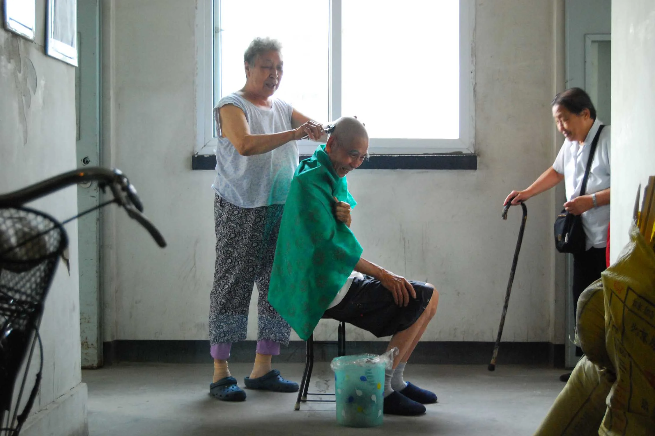  A woman gives her husband a haircut in the hallway of their Beijing apartment on a hot summer morning in 2011. 