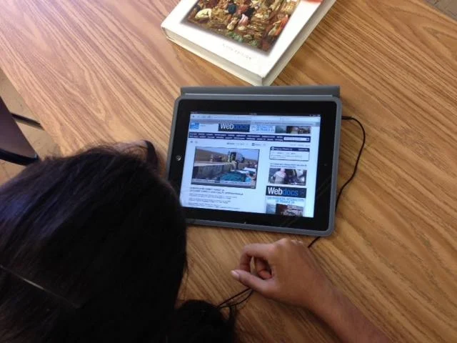 Student listens to French broadcast on an iPad.