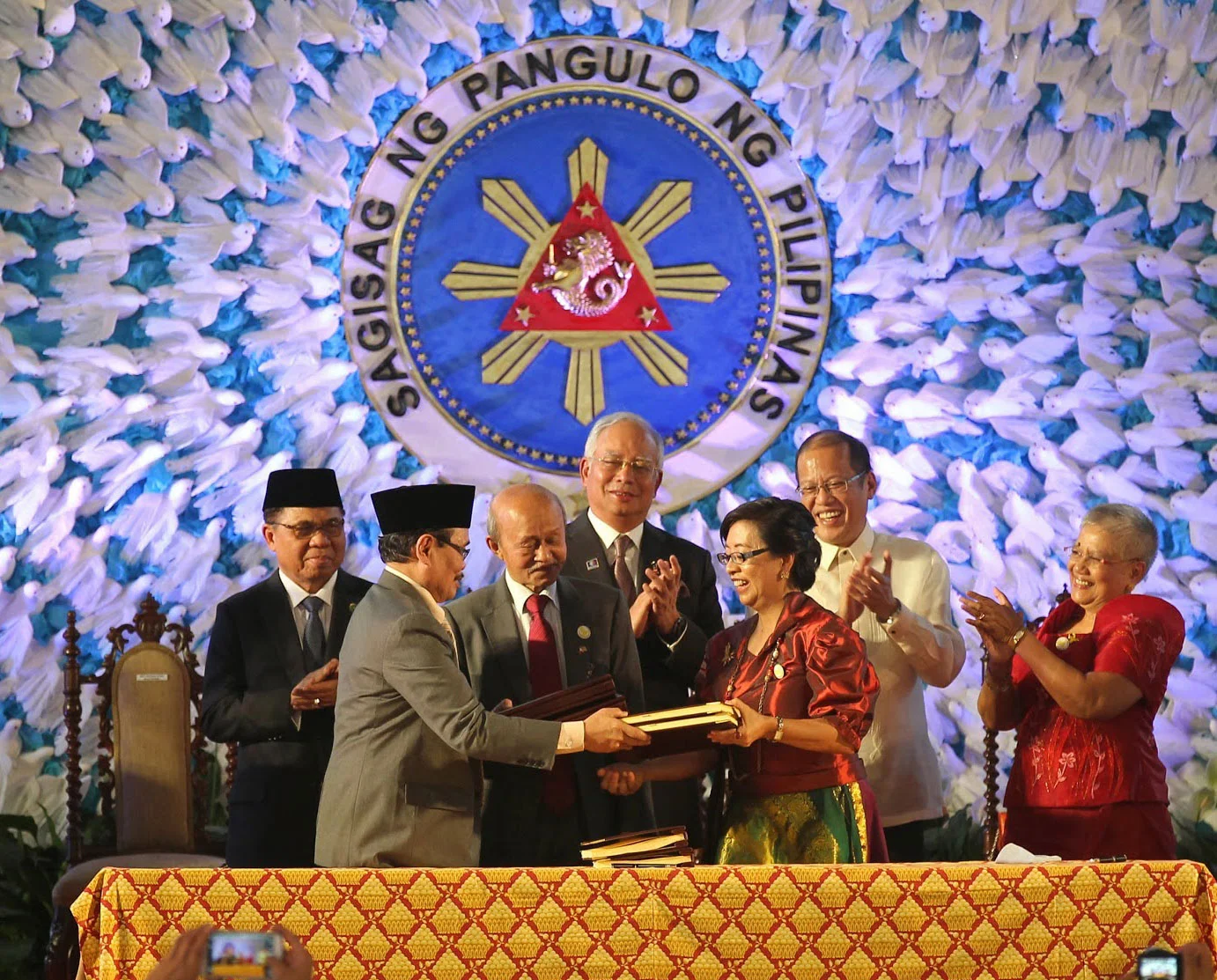 President Benigno Aquino III (back, second from right) and Malaysian Prime Minister Najib Razak (back, center) applaud as peace panel heads Mohagher Iqbal and Miriam Coronel-Ferrer shake hands after the signing of the Comprehensive Agreement on the Bangsamoro at Malacañang last March 27, 2015 (Photo by Gil Nartea, Robert Viñas, Rodolfo Manabat, Malacañang Photo Bureau)