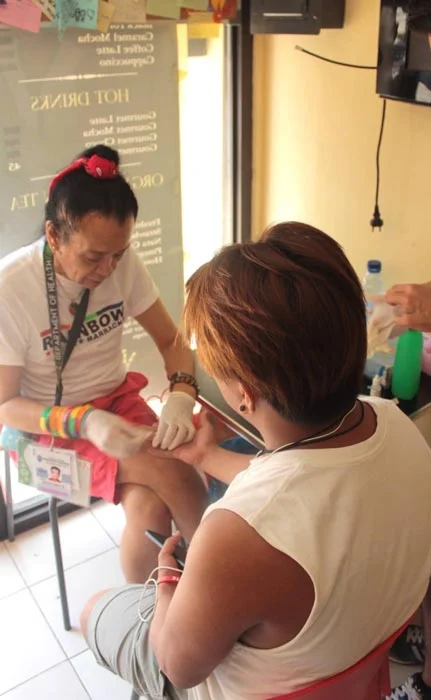 Yabut performing an HIV test on a client (Photo courtesy of Bootz Yabut)