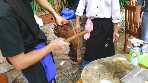 Beating the chicken as part of the Pinikpikan preparation process (Source: pepper.ph )