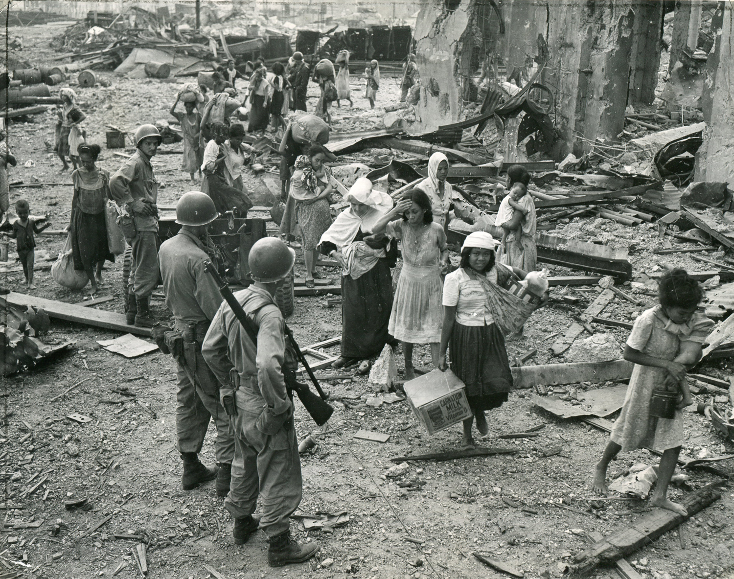 Filipino refugees, many barefoot, pick through the wreckage of north Manila, having just crossed the Pasig River following the fight for the Walled City. The nun carries a motherless infant born just three days earlier. (National Archives)