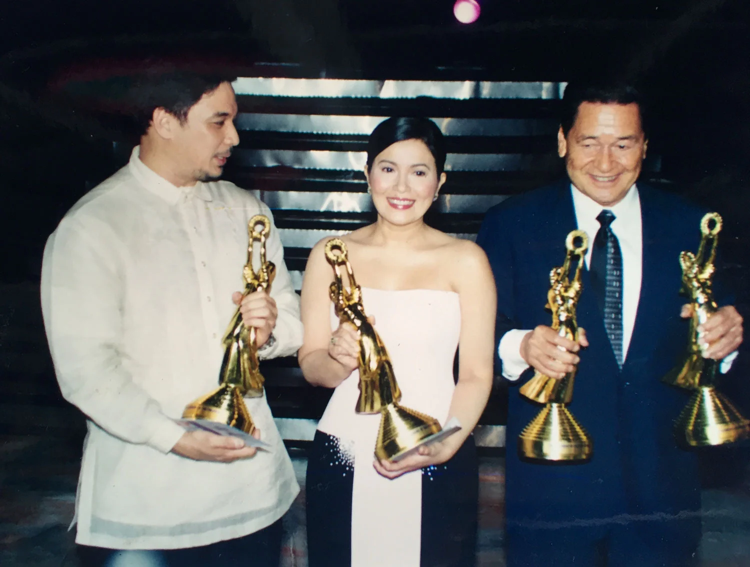 With Ricky Davao and Lorna Tolentino, Eddie Garcia holds his two FAMAS statuettes, one for best supporting actor in Ito Ang Pilipino and the other for best actor in Pinagbuklod ng Langit , both 1969 movies.