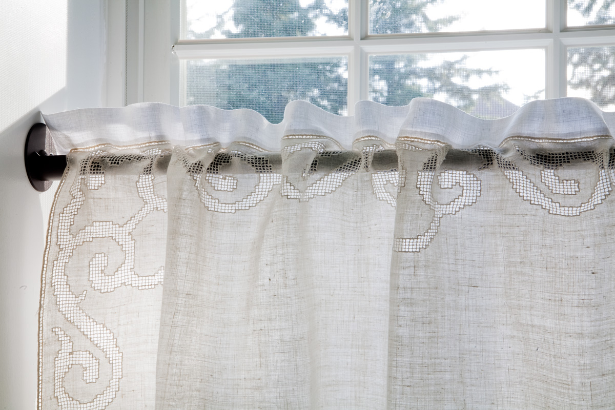  Two vintage table cloths are layered to create a casing for hanging on skinny iron rod and for subtle mix of bright white and cream to tie in with room scheme 