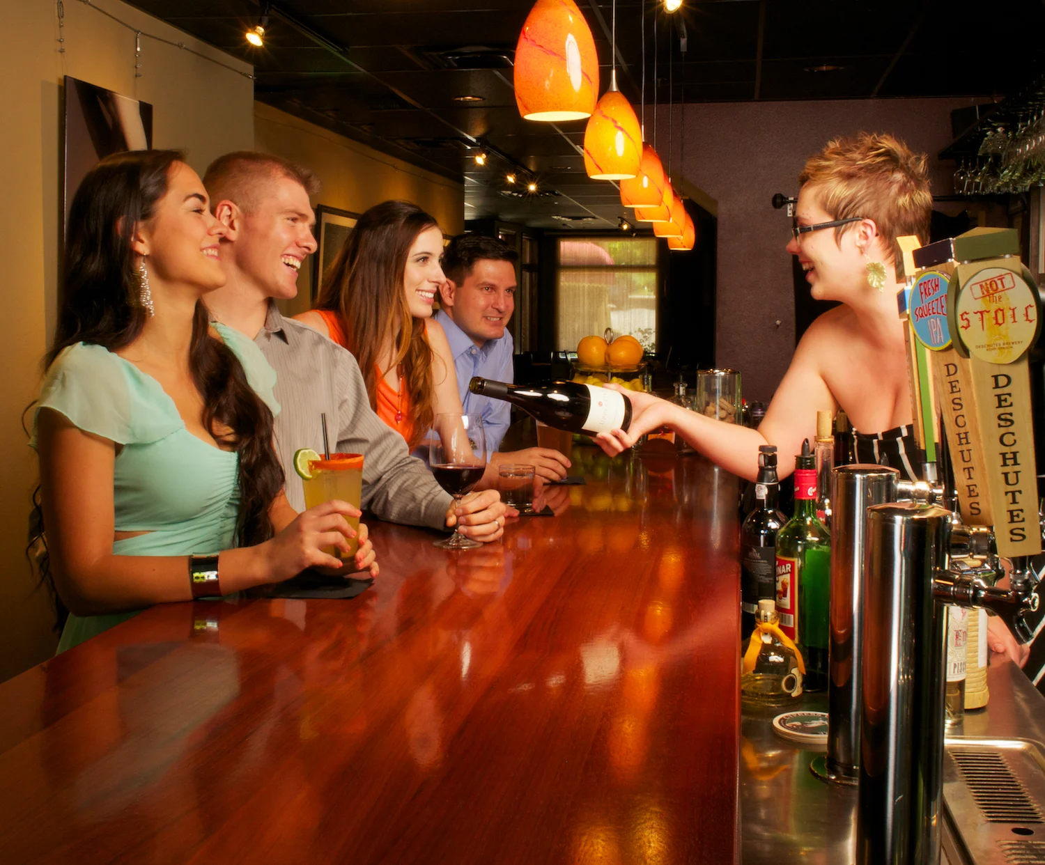 A staged photo with models to highlight happy hour, the variety of drinks available, the look of the bar, and so-on