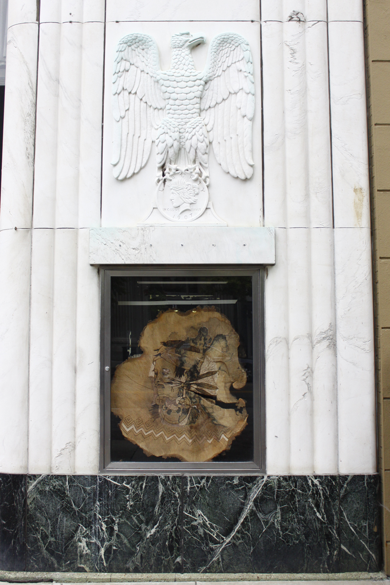  Roots, Ogwehoweh, 2012, downtown Columbus Ohio Arts Pop-Up Project (CAP-UP) Columbus’ Bicentennial, burned native wood portraying portraits of First Nations people in early 1800s, native medicinal plants, dirt, moss, 7' x 25' x 4' (overall installat