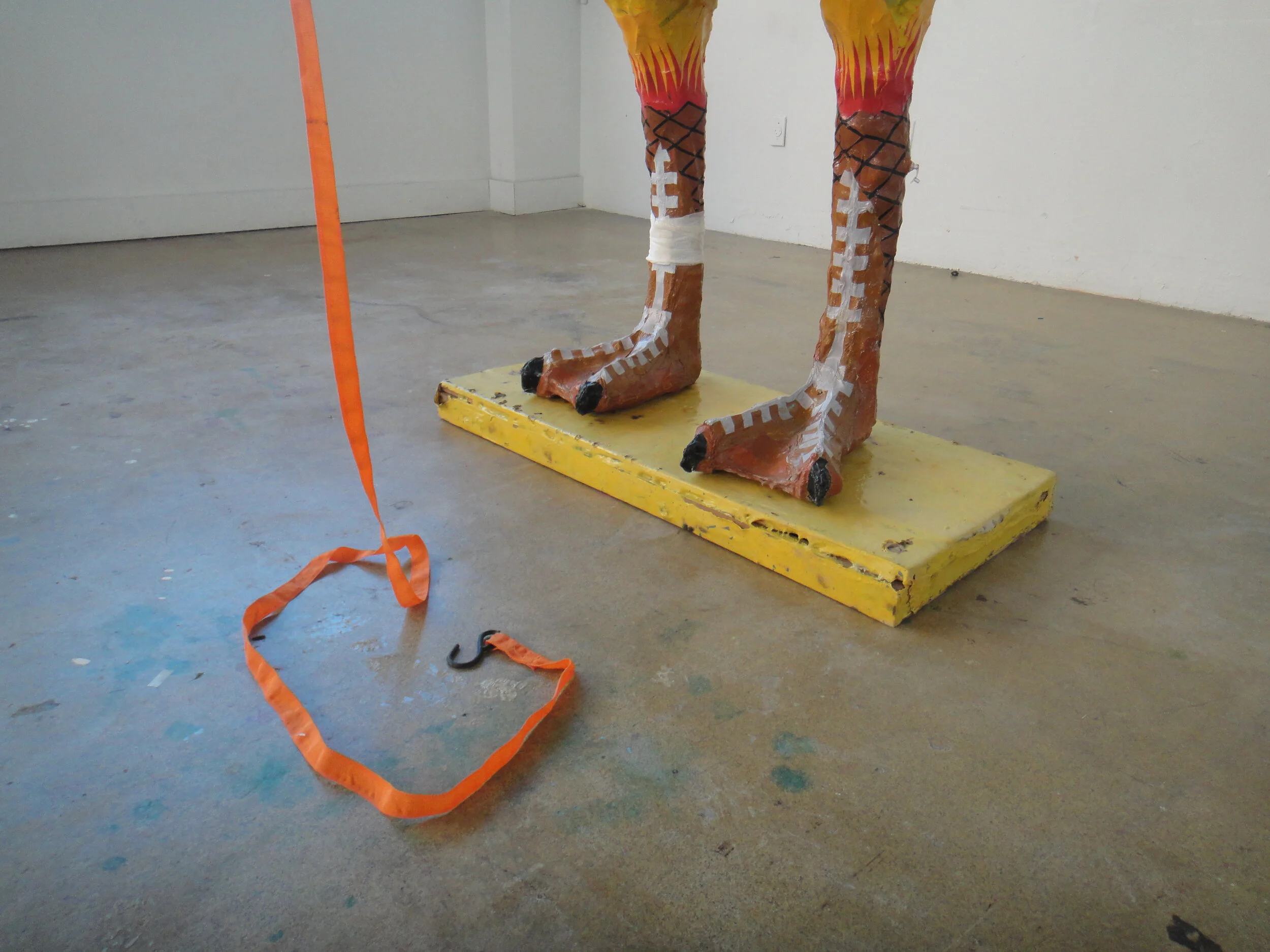  The orange tie on its neck makes it seem alive, as if it were lead to stand on the platform and could leap off at any second. This gives the mascot a sinister quality of exploitation and torture, despite its happy face skin and bright pop colours. T