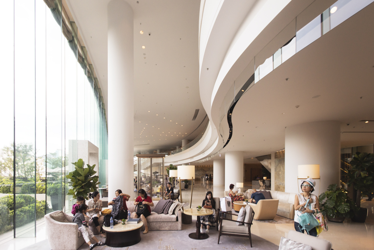 The lobby’s curved glass windows span 26 feet-foot-tall windows will link the manicured outdoors with the interior design