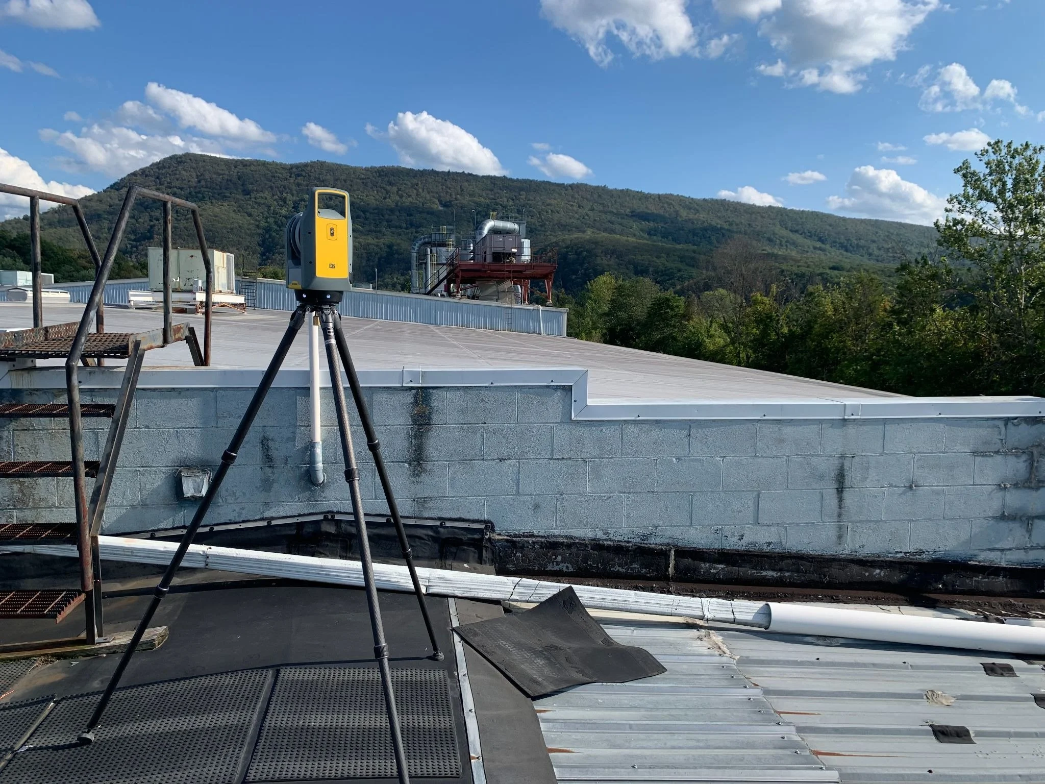 Surveying equipment on a rooftop with a mountain landscape in the background.
