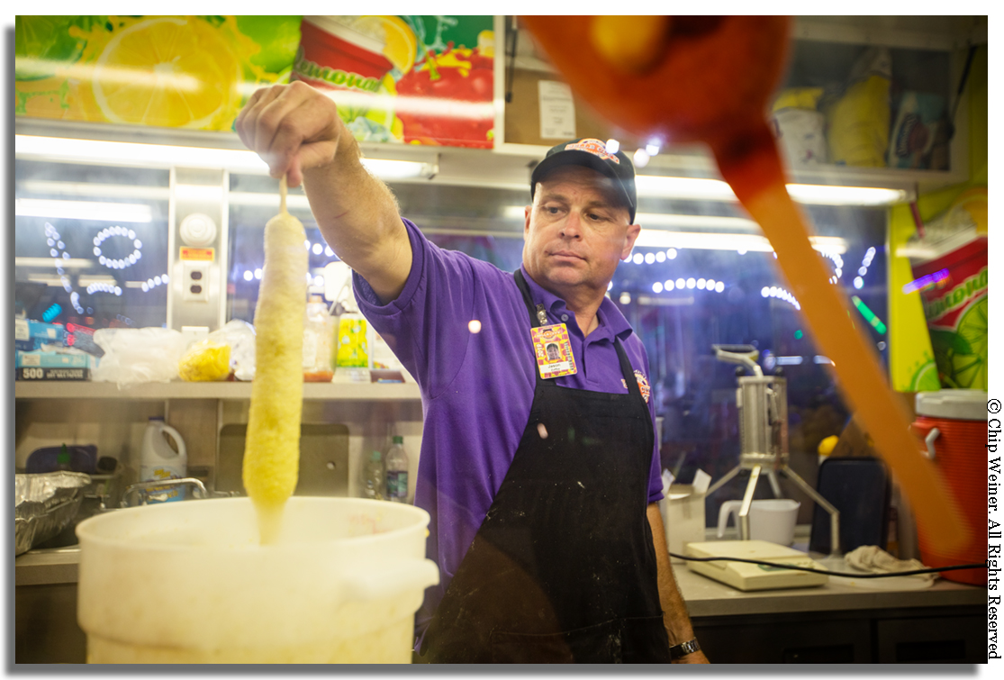 Speaking of corn dogs, what's a fair without a foot-long? Jason Zokka with Potopas Concessions dips a 12 incher in batter before dropping it into the deep fryer. Yes, I did as a matter of fact… with a little mustard.