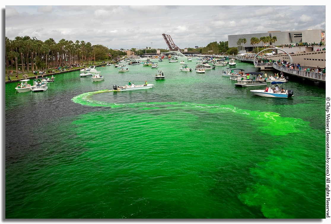 A boat zigzags back and forth dropping the yellow/green liquid dye into the water. The boats prop helps to churn and agitate the mixture.