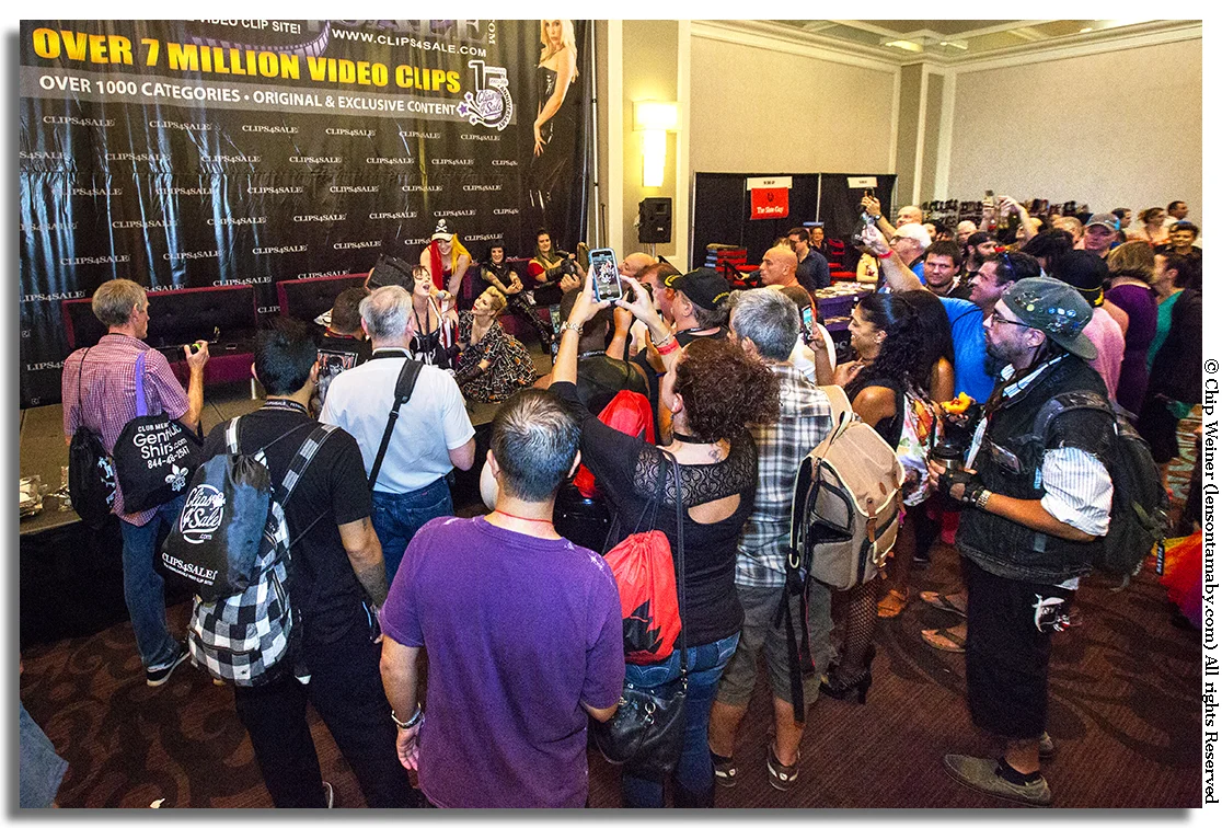 Men and women watch and photograph an equipment demo during Fetish Con 2018.