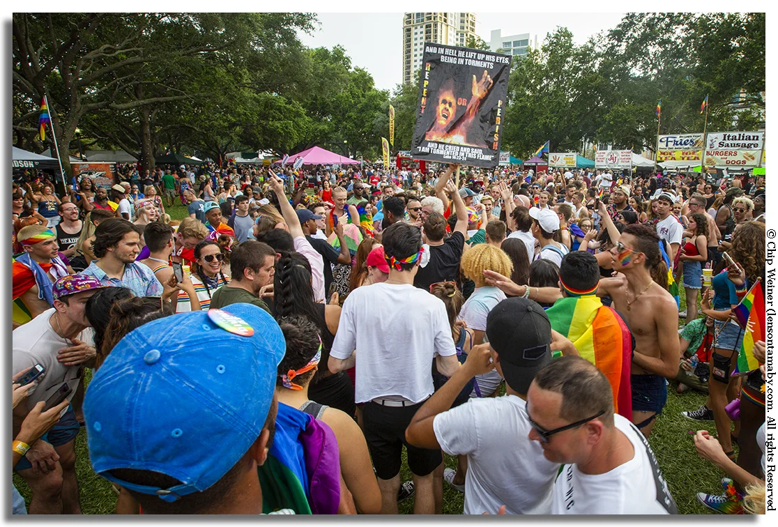 People attending Pride react to a sign condemning sinners to hell in North Straub Park in St Petersburg